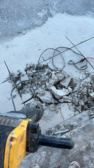 Newly laid Schedule 40 PVC main sewer line in a saw-cut concrete slab trench before backfill and pouring.
