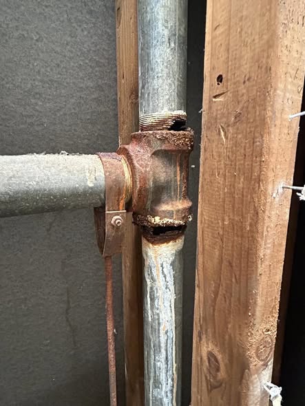 Visual proof: Harmless white vapor escapes from a cracked PVC vent joint inside a wall cavity, pinpointing the exact location of the sewer gas leak.