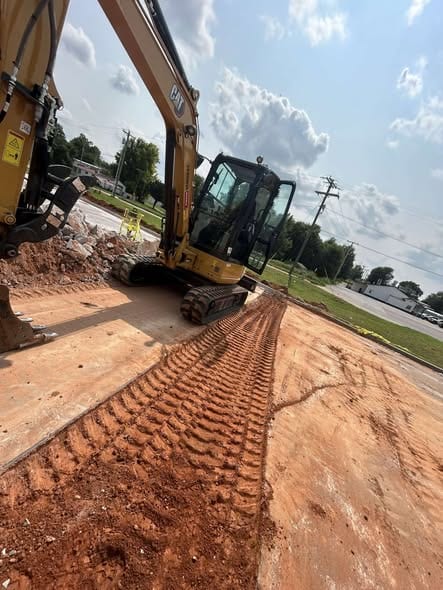 Compacted trench backfill at a commercial site with the mini excavator parked over the line