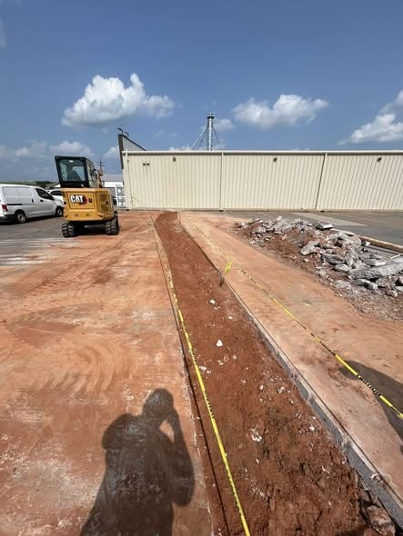 Graded trench line marked off along a commercial building after sewer line work