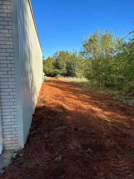 Graded and compacted trench backfill along the wall of a commercial building after sewer work