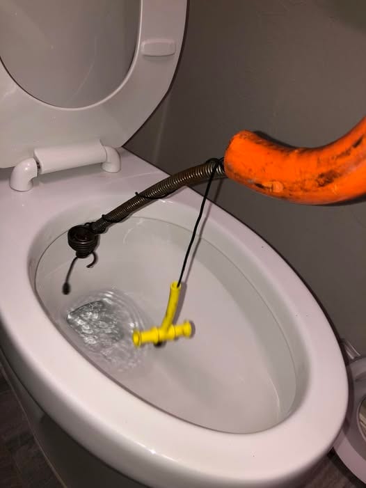 Closet auger feeding into a toilet bowl mid-clearing during a stoppage call