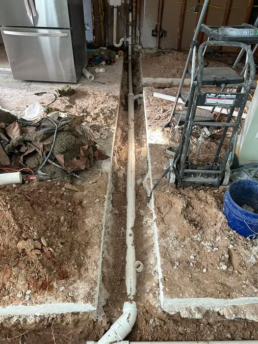 New PVC drain line in a trench cut through the slab inside a home during an under-slab drain repipe