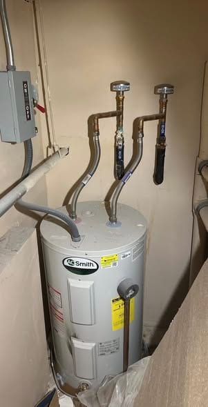 New A.O. Smith electric water heater in a utility closet with flex connectors and isolation valves (duplicate scene of commercial-water-heater-1)