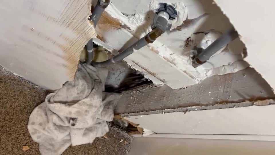 Gray polybutylene lines and fittings beneath a floor, opened up for evaluation