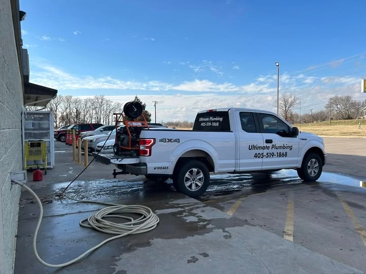 Ultimate Plumbing truck with the hydro jetter unit in the bed and jetting hose coiled out at a commercial job